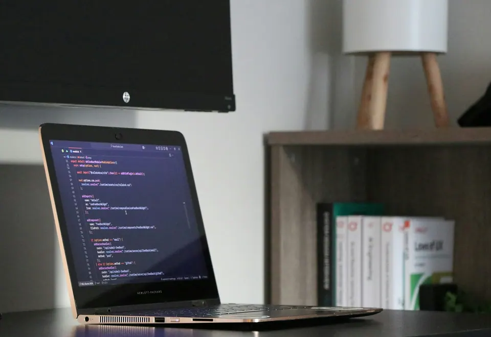 Arbeitsplatz mit Laptop und geöffnetem Programmcode.